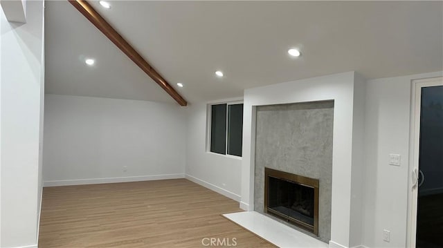 unfurnished living room featuring lofted ceiling with beams, wood finished floors, a fireplace with flush hearth, and recessed lighting