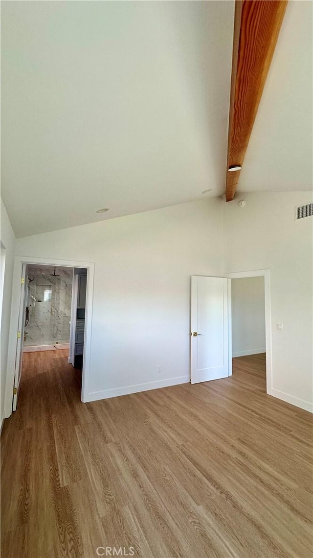 spare room with vaulted ceiling with beams, baseboards, visible vents, and wood finished floors