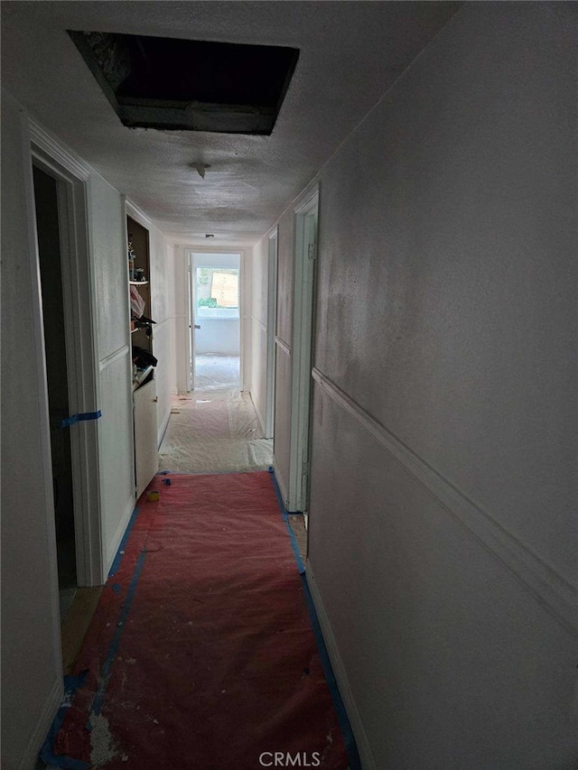 hall featuring carpet flooring and a textured ceiling