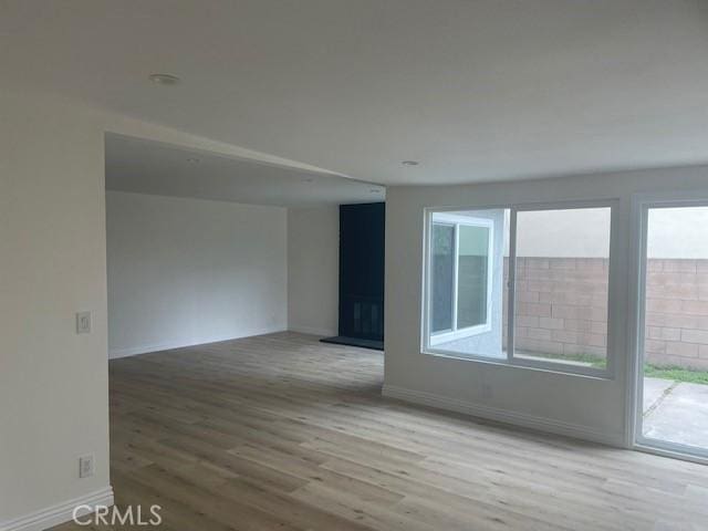 unfurnished room featuring baseboards, plenty of natural light, and wood finished floors