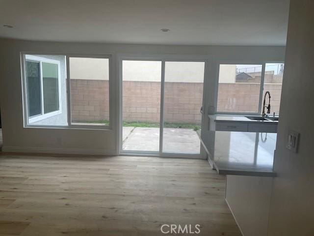 unfurnished living room with wood finished floors, baseboards, and a sink