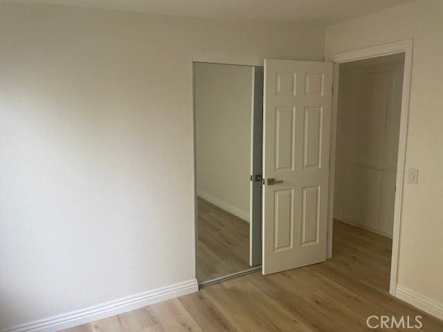 unfurnished bedroom featuring baseboards, light wood-type flooring, and a closet