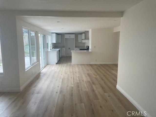 unfurnished living room featuring light wood-style floors, baseboards, and a sink