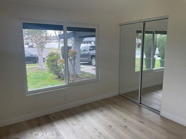 unfurnished bedroom with a closet, multiple windows, and wood finished floors