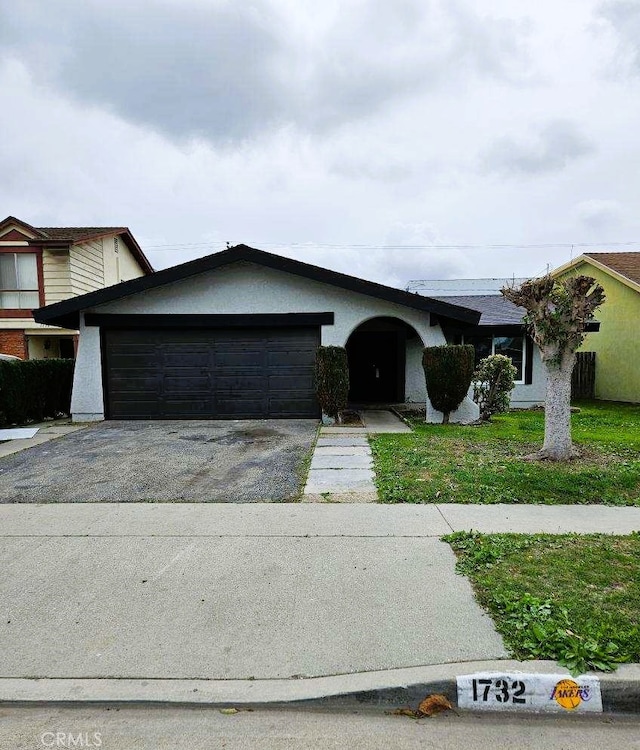 view of front of home featuring aphalt driveway, stucco siding, an attached garage, and a front lawn