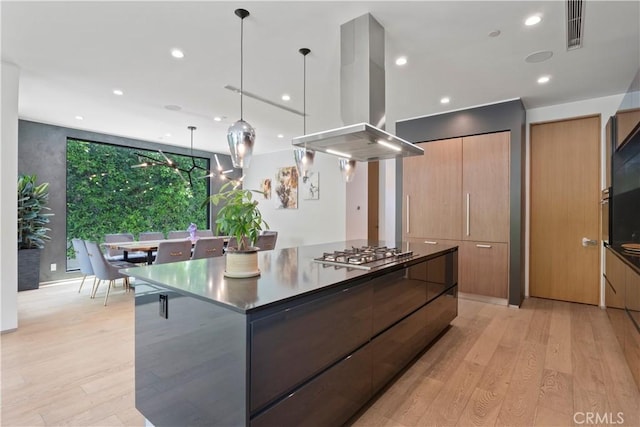 kitchen with island exhaust hood, a large island, light hardwood / wood-style flooring, and stainless steel gas cooktop