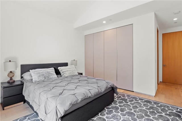 bedroom with light hardwood / wood-style floors, a closet, and lofted ceiling