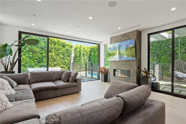 living room featuring a fireplace, light wood-type flooring, and floor to ceiling windows