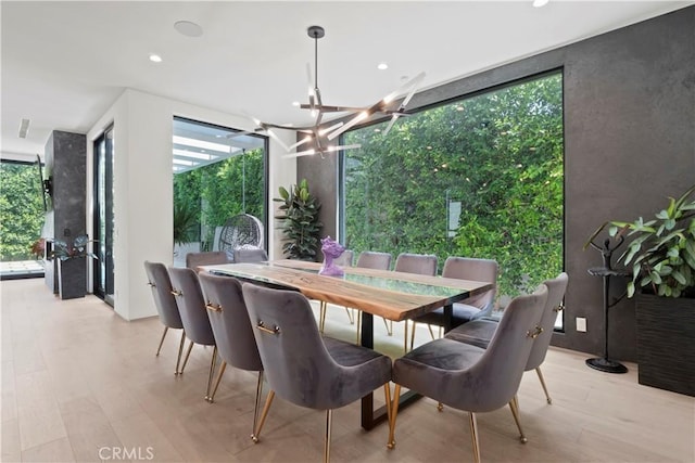 dining room with a notable chandelier, plenty of natural light, and light hardwood / wood-style flooring