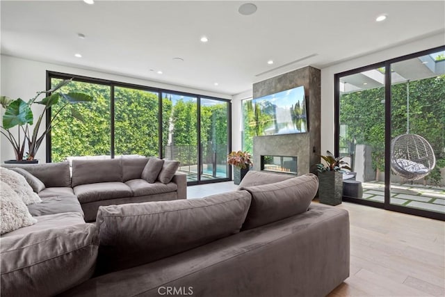 living room featuring light hardwood / wood-style floors, a wall of windows, and a premium fireplace