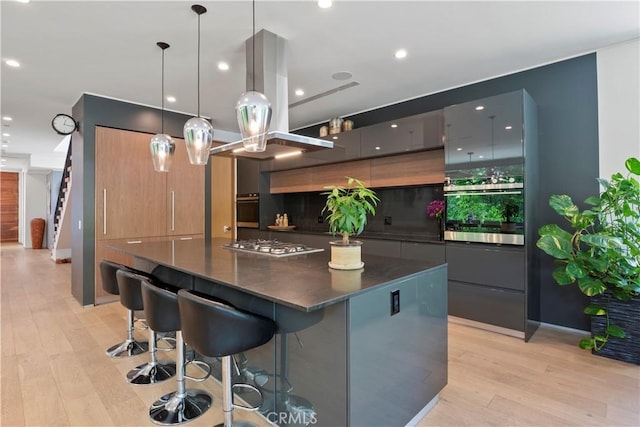 kitchen featuring light hardwood / wood-style flooring, a center island, pendant lighting, and appliances with stainless steel finishes