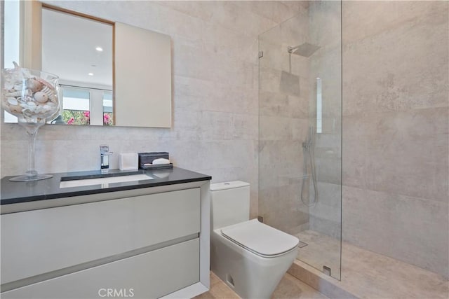 bathroom with tile patterned flooring, vanity, toilet, and tiled shower