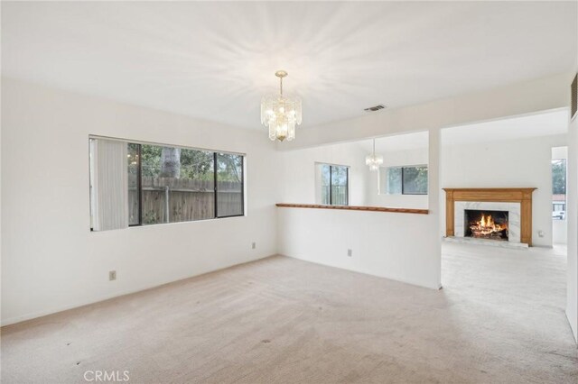 unfurnished living room with plenty of natural light, a fireplace, and light carpet