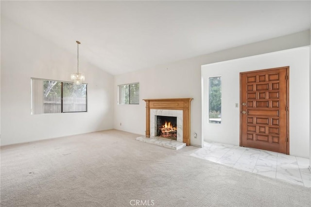 unfurnished living room with a chandelier, light colored carpet, a high end fireplace, and vaulted ceiling