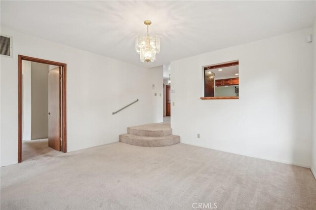 carpeted spare room featuring an inviting chandelier