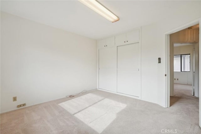 unfurnished bedroom featuring a closet and light colored carpet