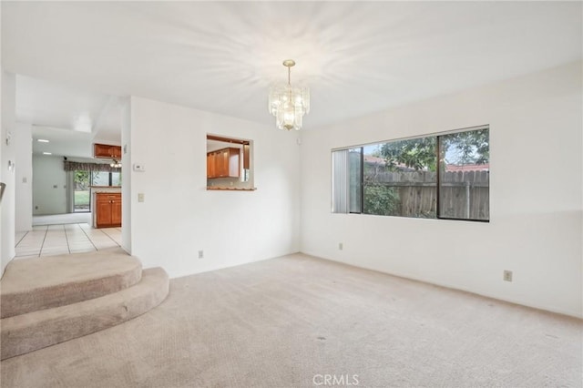 unfurnished room featuring a notable chandelier, plenty of natural light, and light colored carpet