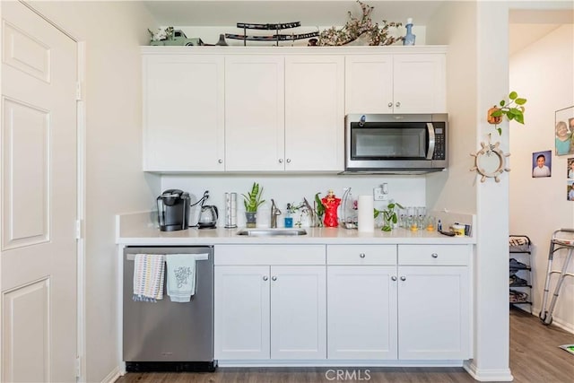 kitchen with white cabinetry, sink, stainless steel appliances, and hardwood / wood-style flooring