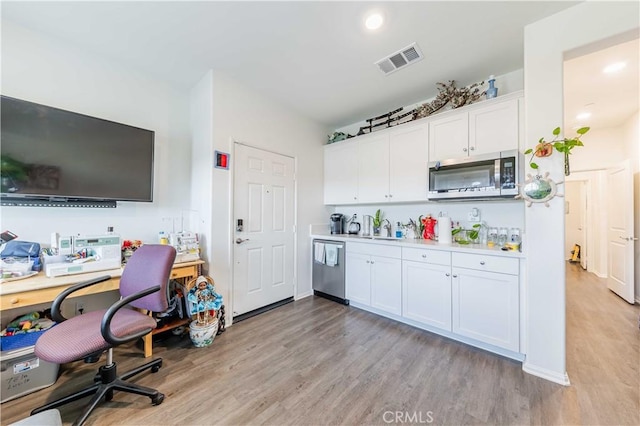 kitchen featuring appliances with stainless steel finishes, light hardwood / wood-style floors, white cabinetry, and sink