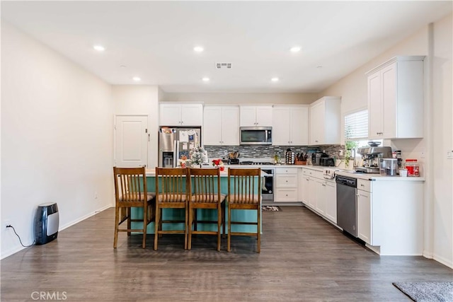 kitchen featuring white cabinetry, a center island, stainless steel appliances, and dark hardwood / wood-style floors