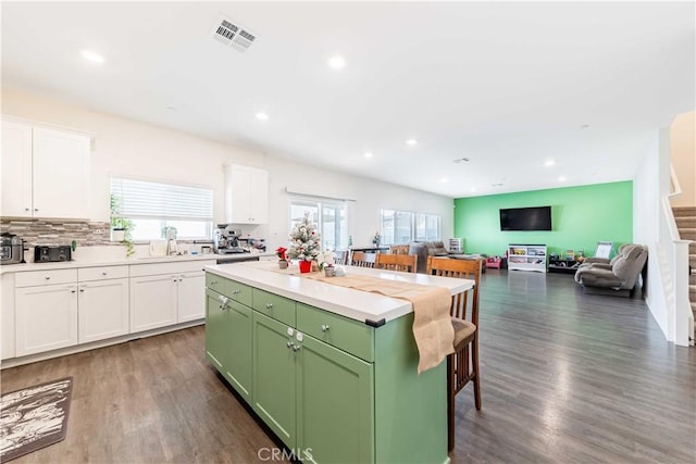 kitchen with white cabinets, dark hardwood / wood-style flooring, a kitchen island, and green cabinets