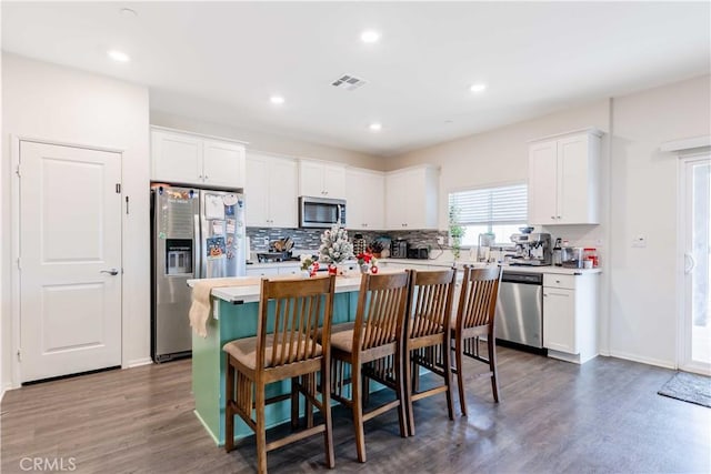 kitchen with white cabinets, a center island, stainless steel appliances, and dark wood-type flooring