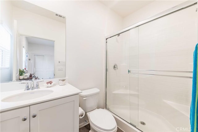 bathroom with vanity, toilet, and a shower with door