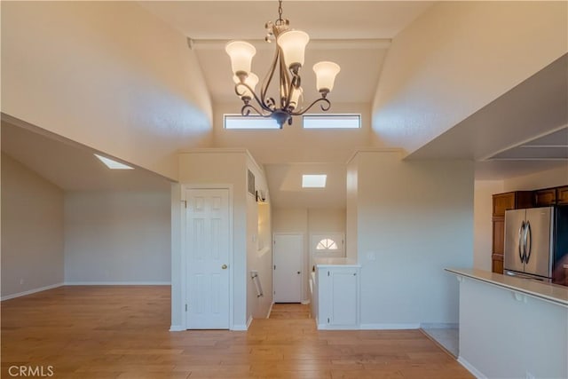 interior space with a towering ceiling, a notable chandelier, and light hardwood / wood-style floors