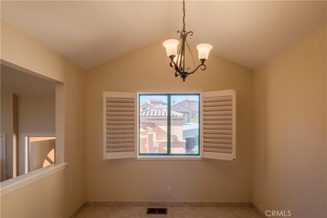 empty room with lofted ceiling and a notable chandelier