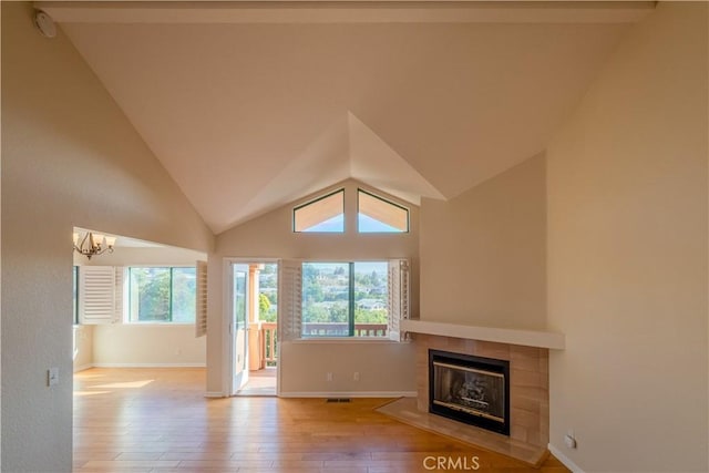 unfurnished living room featuring a fireplace, light hardwood / wood-style floors, a chandelier, and plenty of natural light