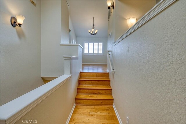 stairs featuring a chandelier and hardwood / wood-style floors