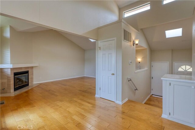 unfurnished living room with lofted ceiling, a fireplace, and light hardwood / wood-style flooring