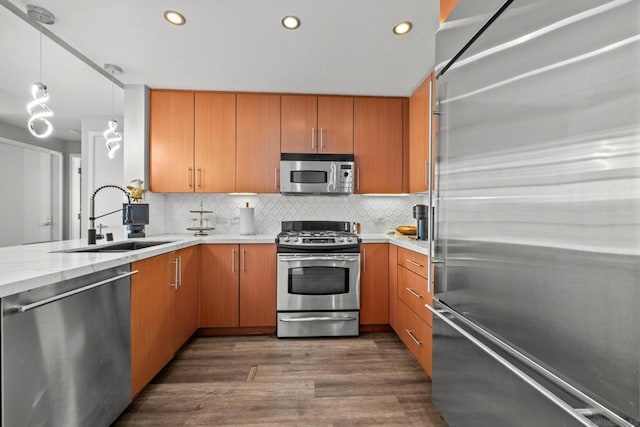 kitchen featuring sink, tasteful backsplash, dark hardwood / wood-style floors, kitchen peninsula, and appliances with stainless steel finishes