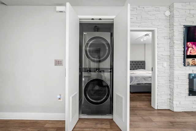 laundry area featuring wood-type flooring and stacked washing maching and dryer