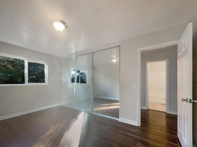 unfurnished bedroom with a closet and dark hardwood / wood-style floors