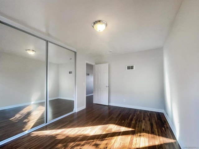 unfurnished bedroom featuring a closet and dark wood-type flooring