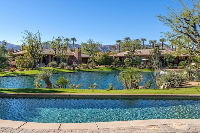 view of pool with a water and mountain view and a yard