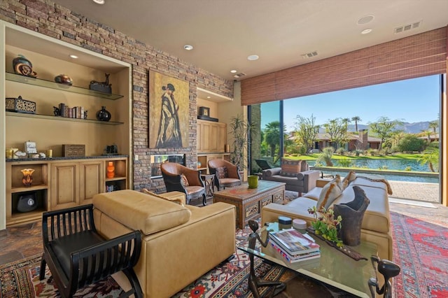 living room with a fireplace, a water view, and built in shelves