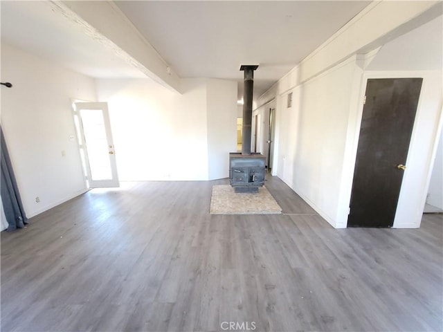 23699 Mclane Ave, Corning, CA 96021 - unfurnished living room featuring a wood stove, wood finished floors, and baseboards
