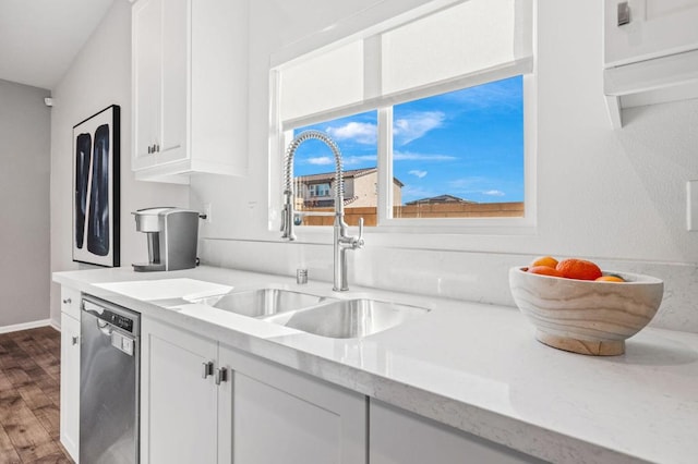 kitchen with light stone countertops, white cabinets, sink, wood-type flooring, and dishwasher