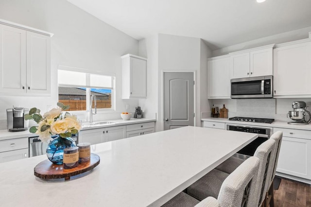 kitchen featuring white cabinets, dark hardwood / wood-style flooring, a breakfast bar area, and appliances with stainless steel finishes