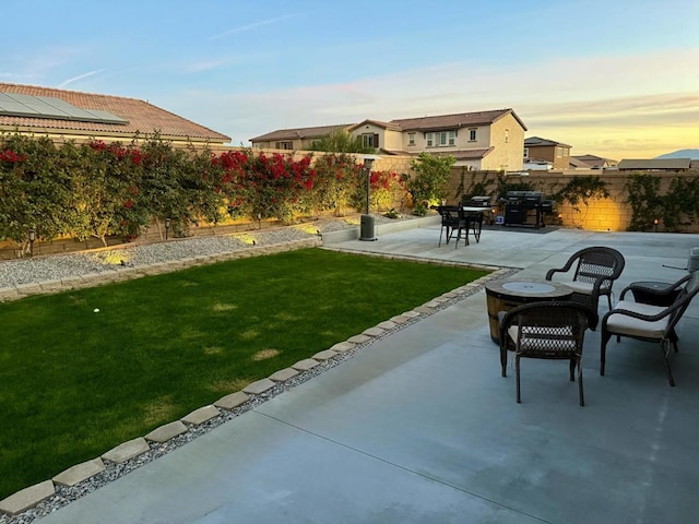 patio terrace at dusk featuring area for grilling and a yard