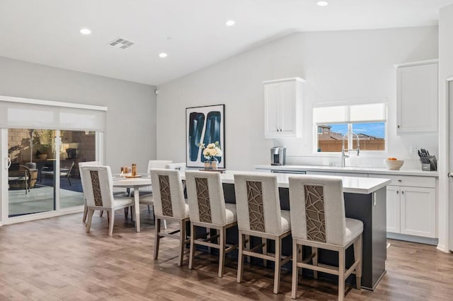 kitchen with white cabinets, a kitchen island, lofted ceiling, and hardwood / wood-style flooring