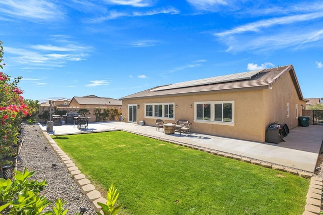 rear view of house with a patio area, a yard, and solar panels