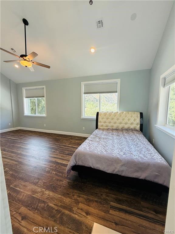 bedroom featuring dark hardwood / wood-style floors, vaulted ceiling, and ceiling fan