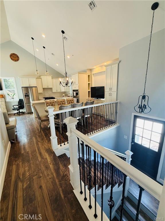 stairs featuring hardwood / wood-style flooring, high vaulted ceiling, and a chandelier