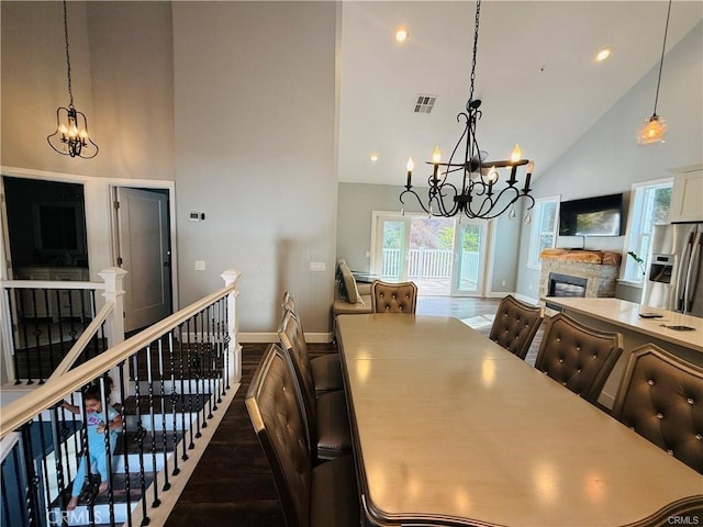 dining room featuring hardwood / wood-style floors, a stone fireplace, and high vaulted ceiling