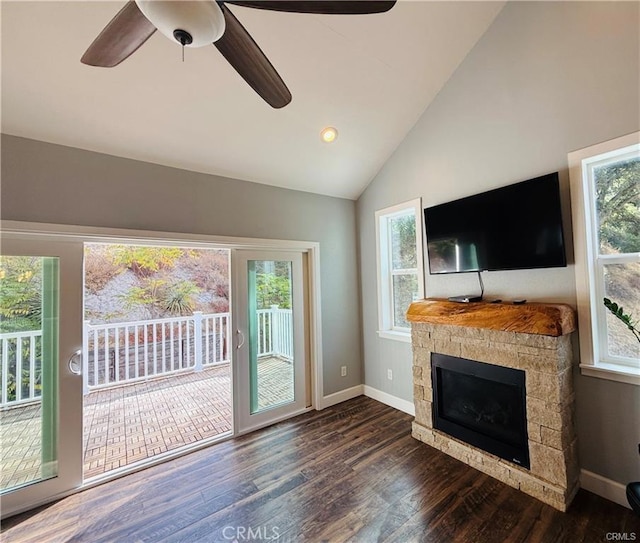 unfurnished living room with a stone fireplace, ceiling fan, dark hardwood / wood-style floors, and vaulted ceiling