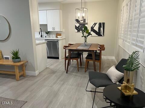 dining area featuring light wood-type flooring, sink, and an inviting chandelier