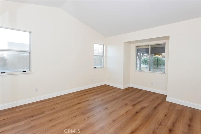 spare room with lofted ceiling and light wood-type flooring